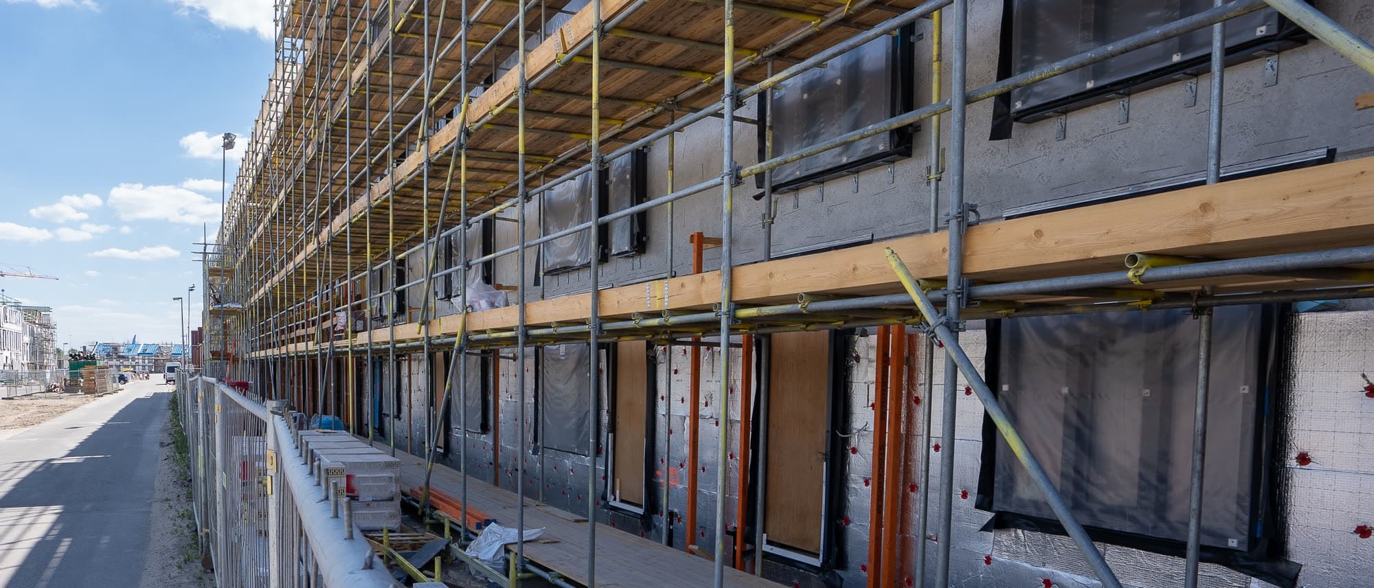 Gerüst entlang einer Fassade mit geklebten und gedübelten Dämmplatten
