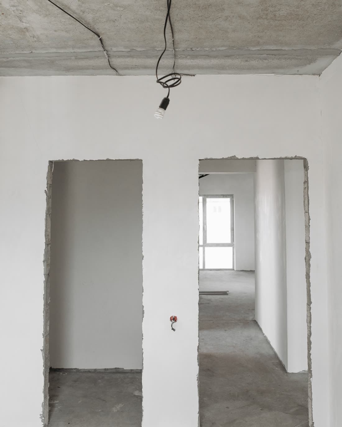 Innenausbau: frisch verputzte Wände mit ausgebrochenen Türöffnungen und roher Betondecke
